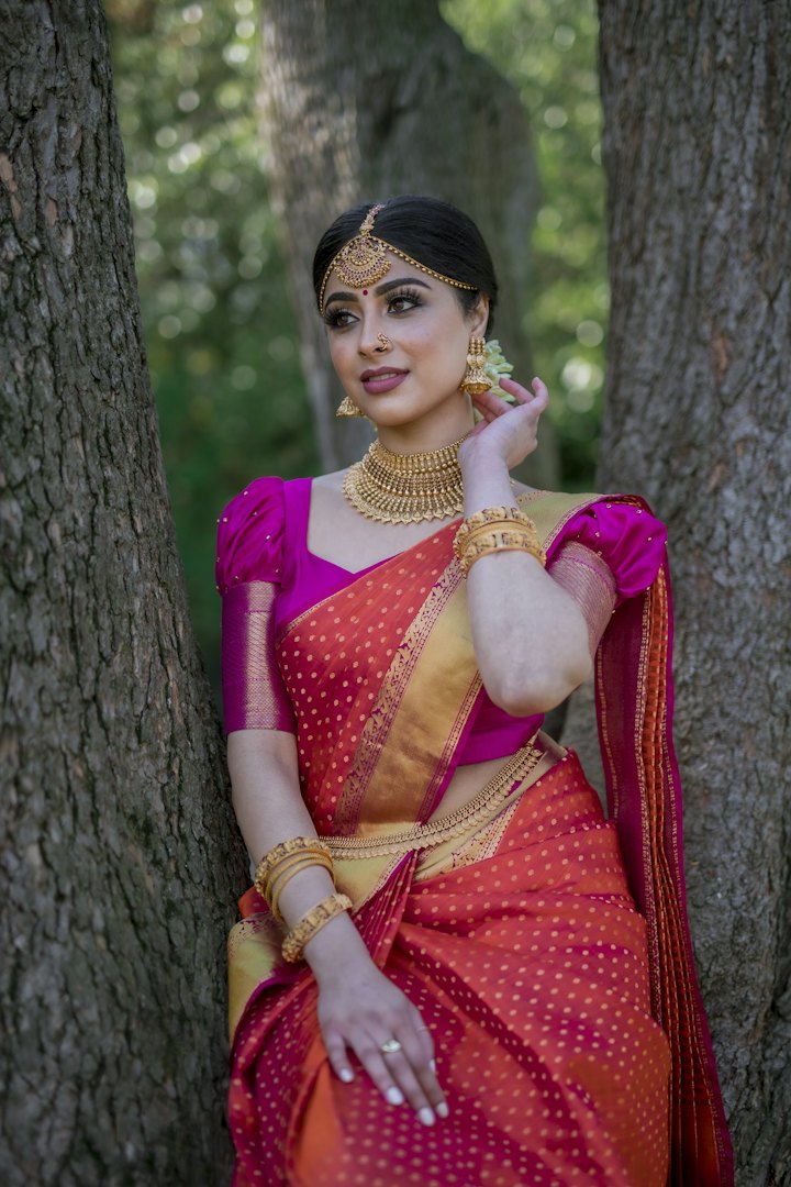 A bride in a red and gold silk saree with traditional jewellery