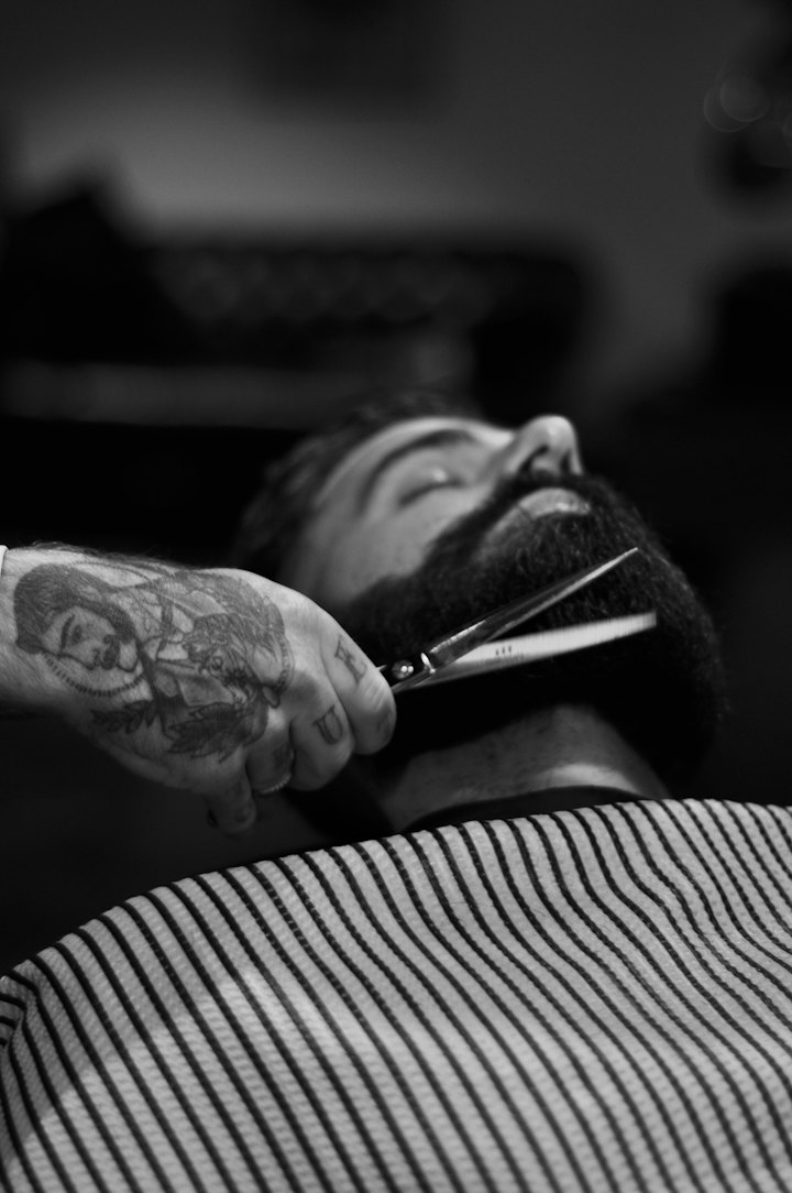 Black-and-white photo of a full beard being trimmed with scissors