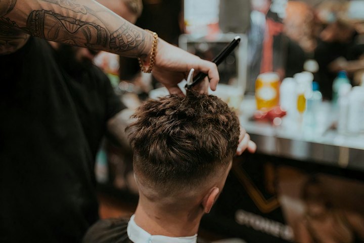 A barber cuts a man's textured hair with scissors