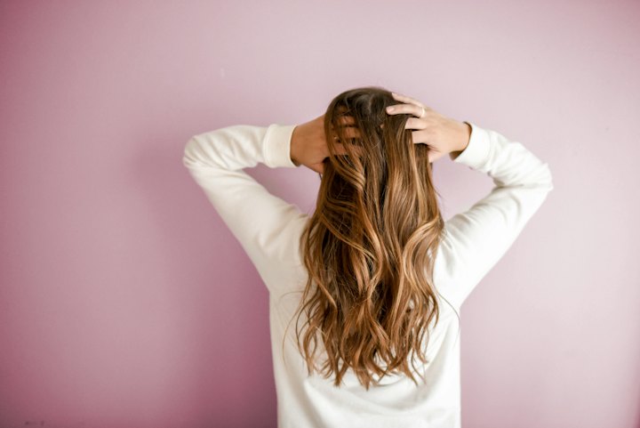 A woman runs her hands through long, wavy brown hair