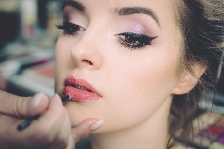 A makeup artist applies lip colour with a fine brush