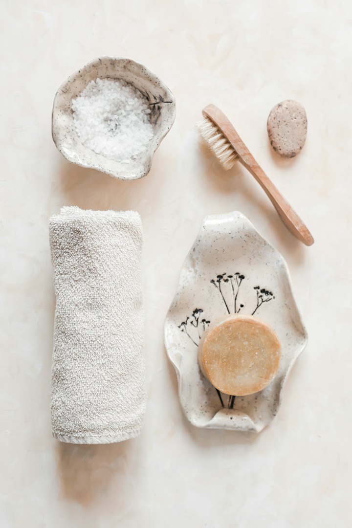 Spa essentials: a folded towel, bath salts, soap and a wooden brush