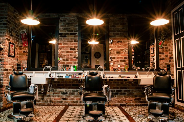A warm grooming lounge with leather chairs, brick walls and pendant lights