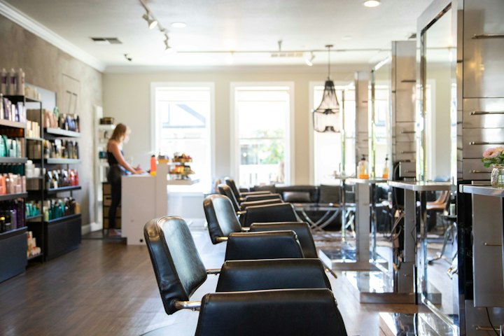 A sunlit studio floor with styling chairs, mirrors and wooden floors