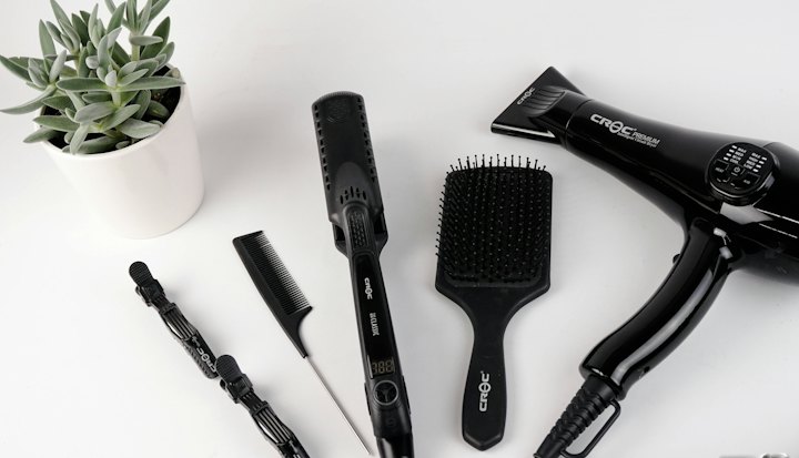Brushes, combs and a hair dryer arranged on a white workstation