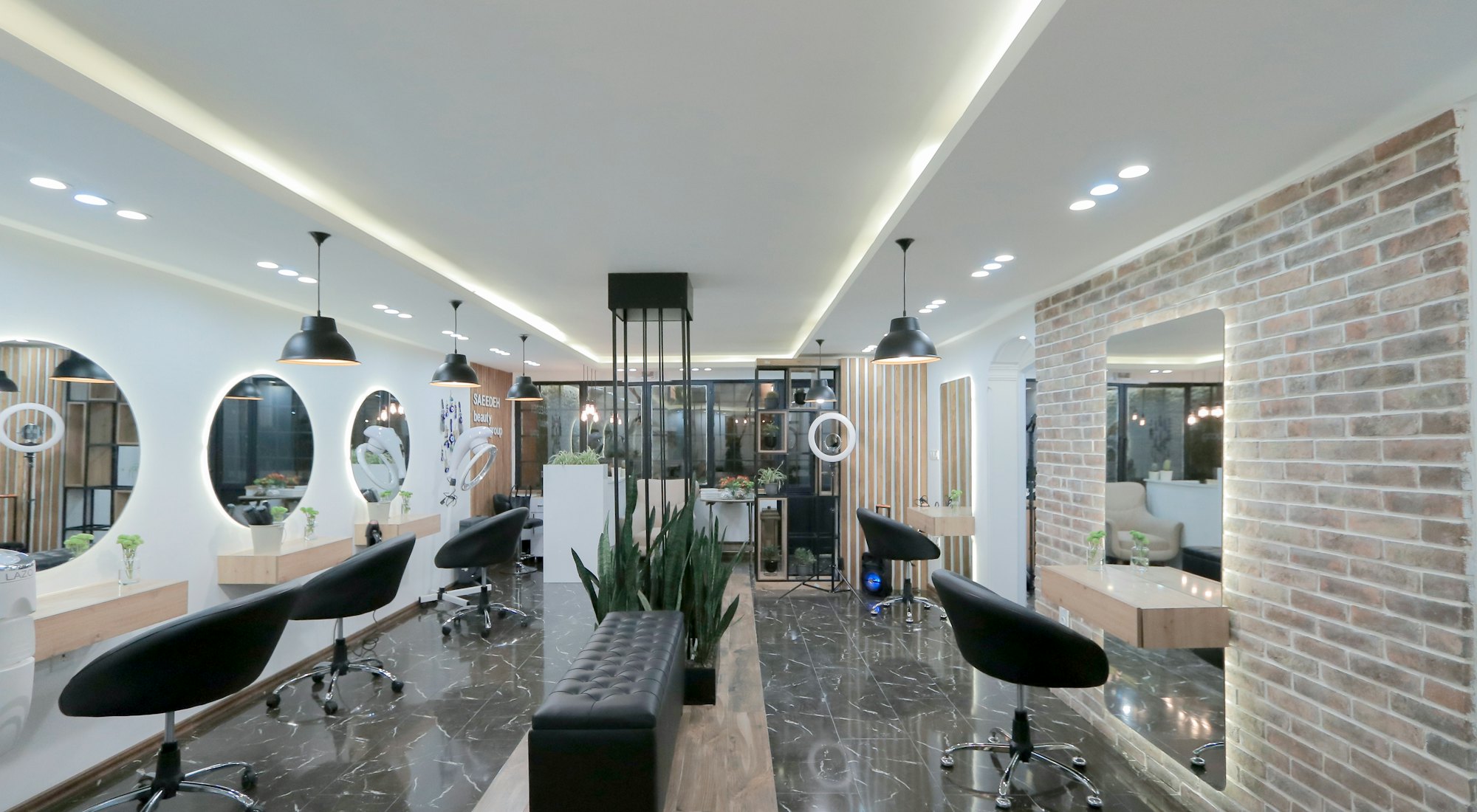 A long, modern studio interior with styling chairs, mirrors and warm lighting