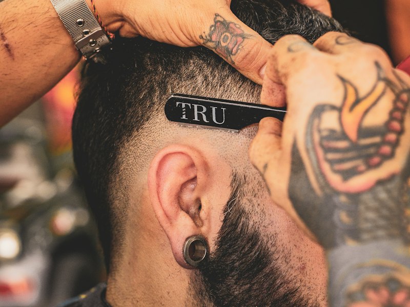 A beard being combed and shaped in a barber chair