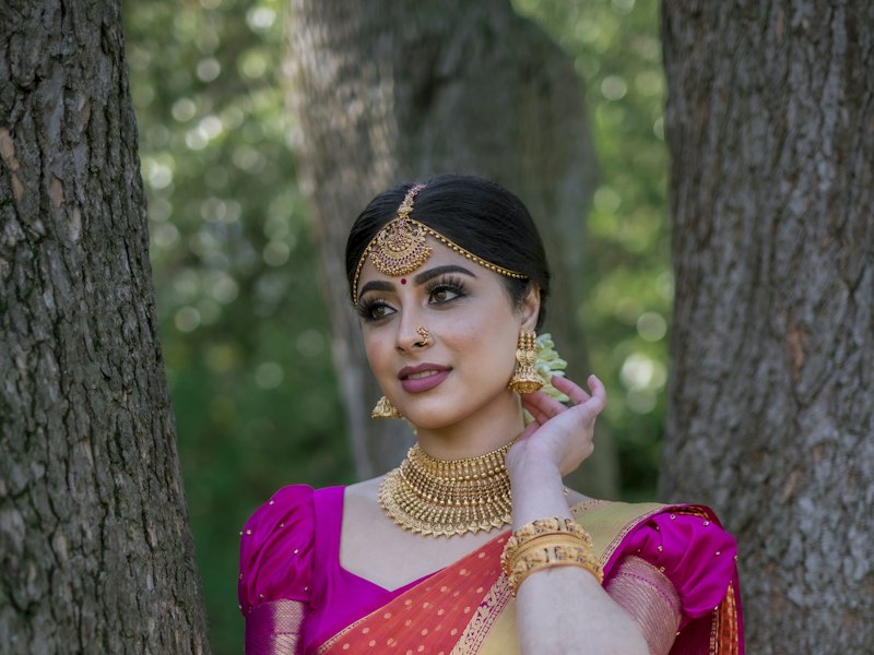 A bride in a red and gold saree with traditional jewellery and bridal makeup