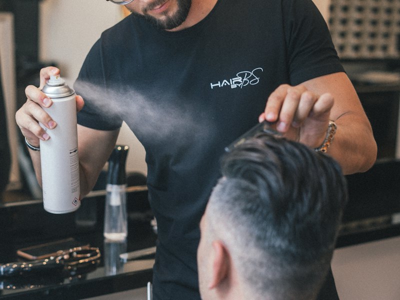 A groomer mists a man's hair with a conditioning spray
