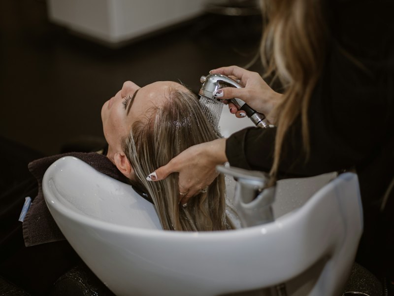 A client relaxes at a basin while her hair is rinsed
