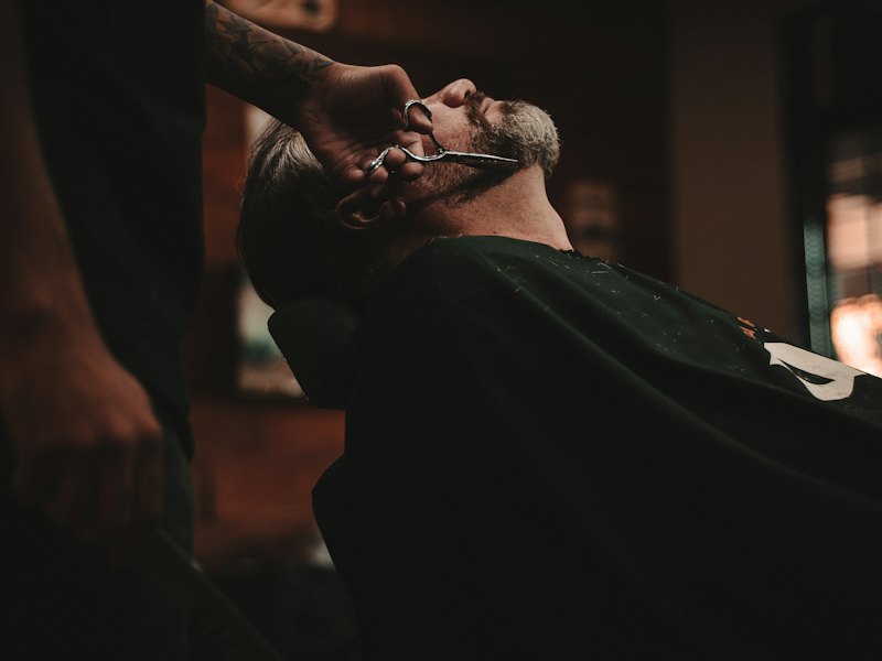 A man reclines in a grooming chair with his eyes closed during a treatment