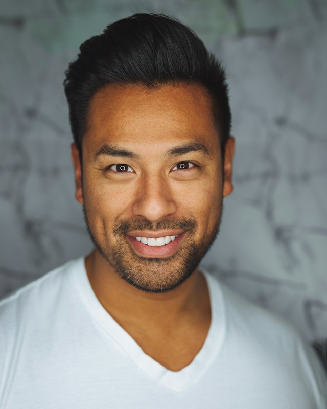 Portrait of a smiling man with short dark hair and a light beard (stock photo for the fictional profile of Arjun)