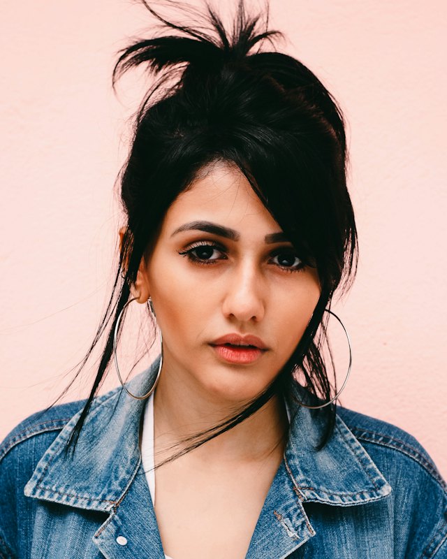 Portrait of a woman with long dark hair wearing a denim jacket (stock photo for the fictional profile of Meera)